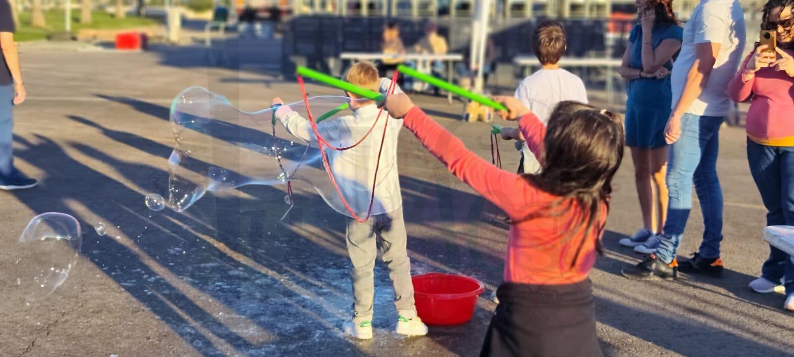 niños jugando con pompas gigantes durante actividades infantiles en evento fallero