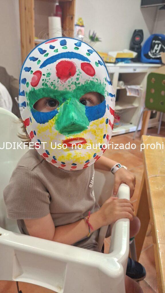 Enric, niño con mutación genética CTBP1, mostrando una máscara pintada durante un taller de ocio educativo inclusivo de LUDIKFEST.